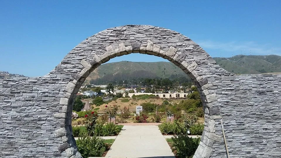 A circular stone arch framing the garden and hills beyond