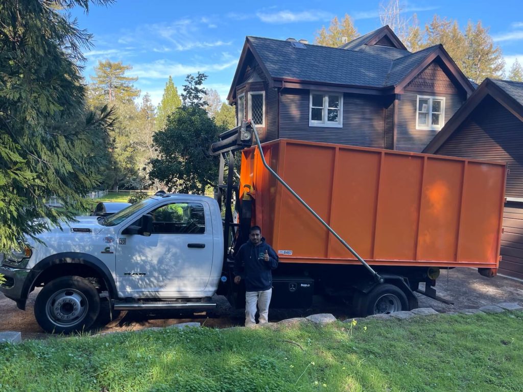 Founder Jaime Perez beside a James Junk Removal truck at a residential job