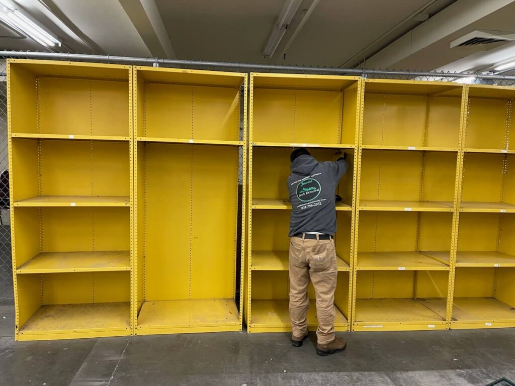 James Junk Removal team member taking apart yellow shelving inside a commercial building