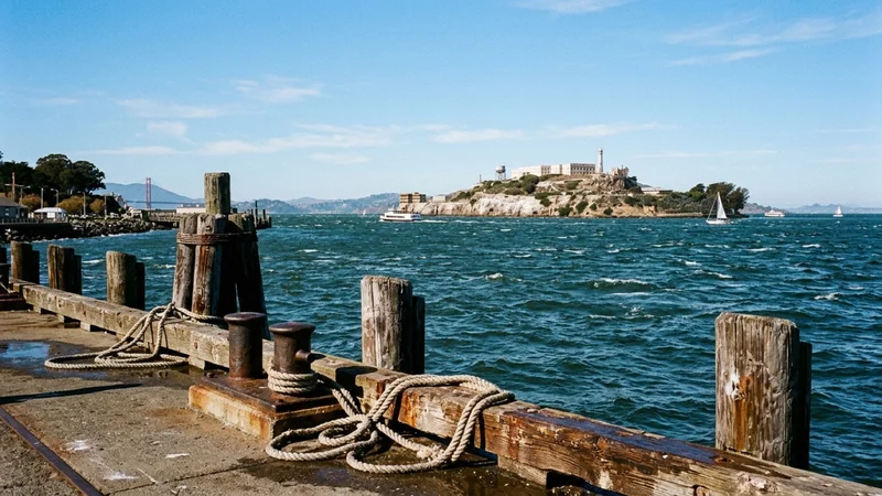 Alcatraz Island across San Francisco Bay with the ferry dock and pilings visible in the foreground