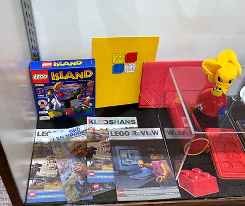 A 1997 LEGO Island PC game box, a vintage four-brick folder and internal LEGO company magazines including Klodshans, LEGO Review and a memorial issue for Godtfred Kirk Christiansen.