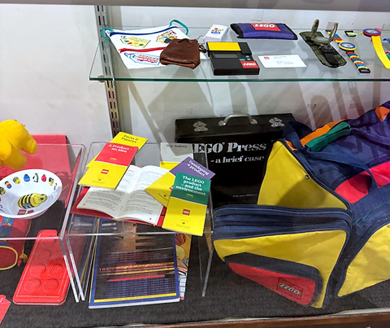 An archival LEGO Press briefcase, internal company booklets on product design and environmental standards, and vintage memorabilia from Dr. Julian Gomez’s collection.