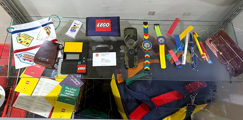 Vintage LEGO brick-link watches, a LEGO calculator, pens, a wallet and a former LEGO Group chief scientist business card from Dr. Julian Gomez’s collection.