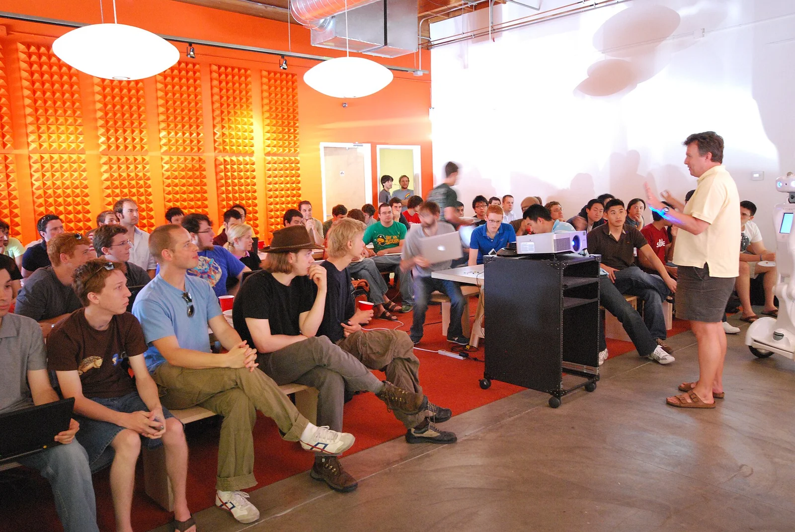Paul Graham speaking to startup founders gathered on benches with laptops during Y Combinator’s Summer 2009 Prototype Day session.