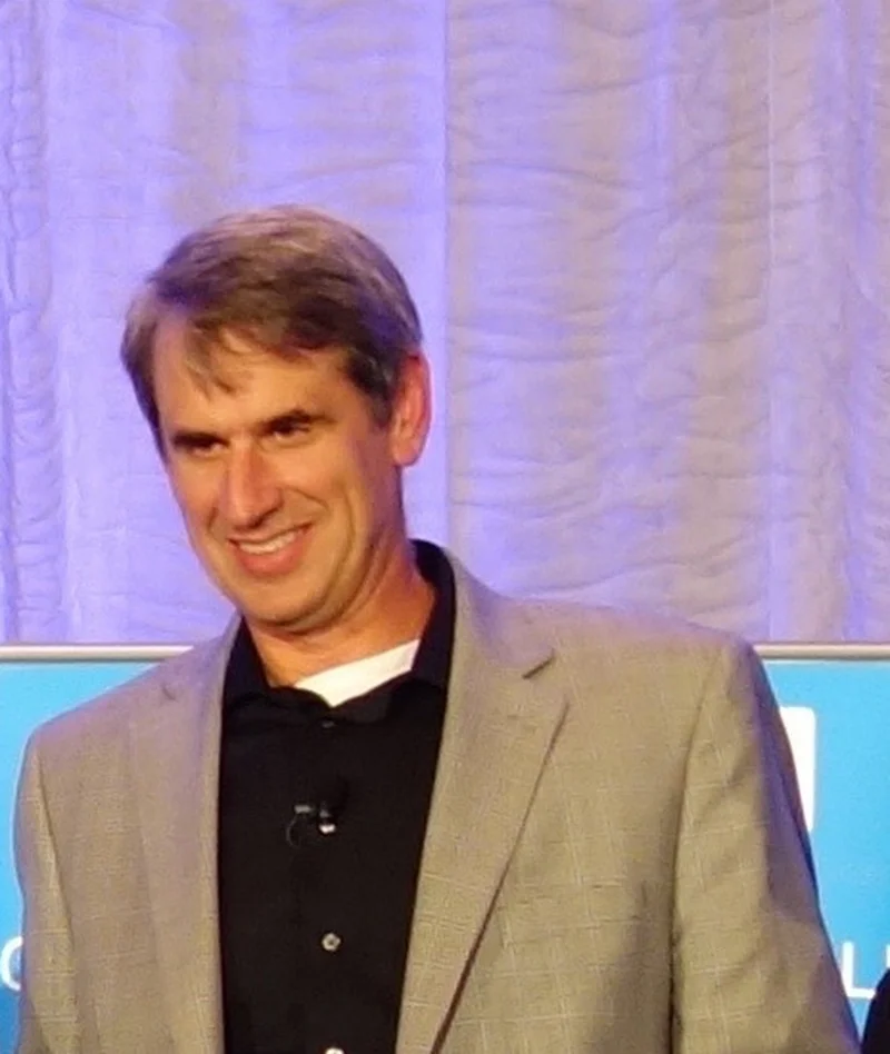 Bill Gurley smiling on stage in a grey blazer and black shirt at the Churchill Club Top 10 Tech Trends debate