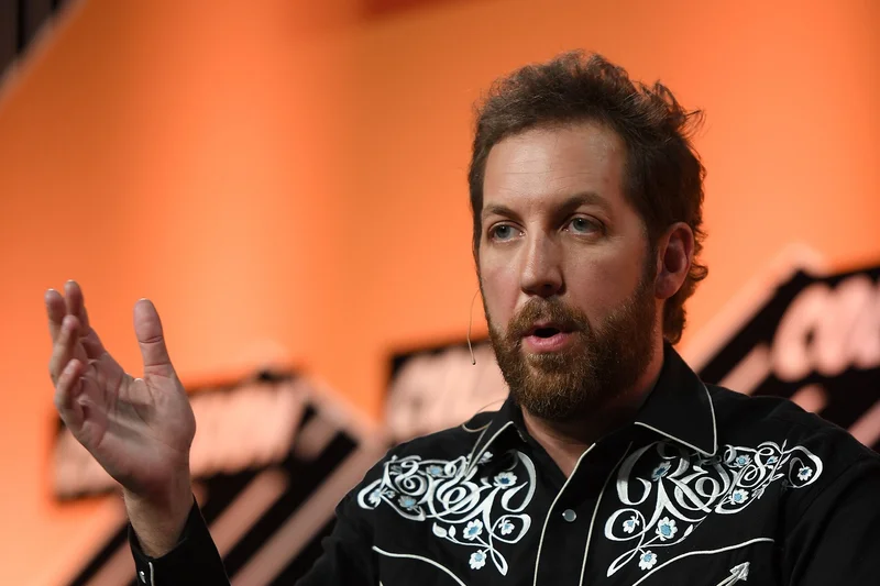 Chris Sacca speaking on stage in an embroidered black Western shirt at Collision